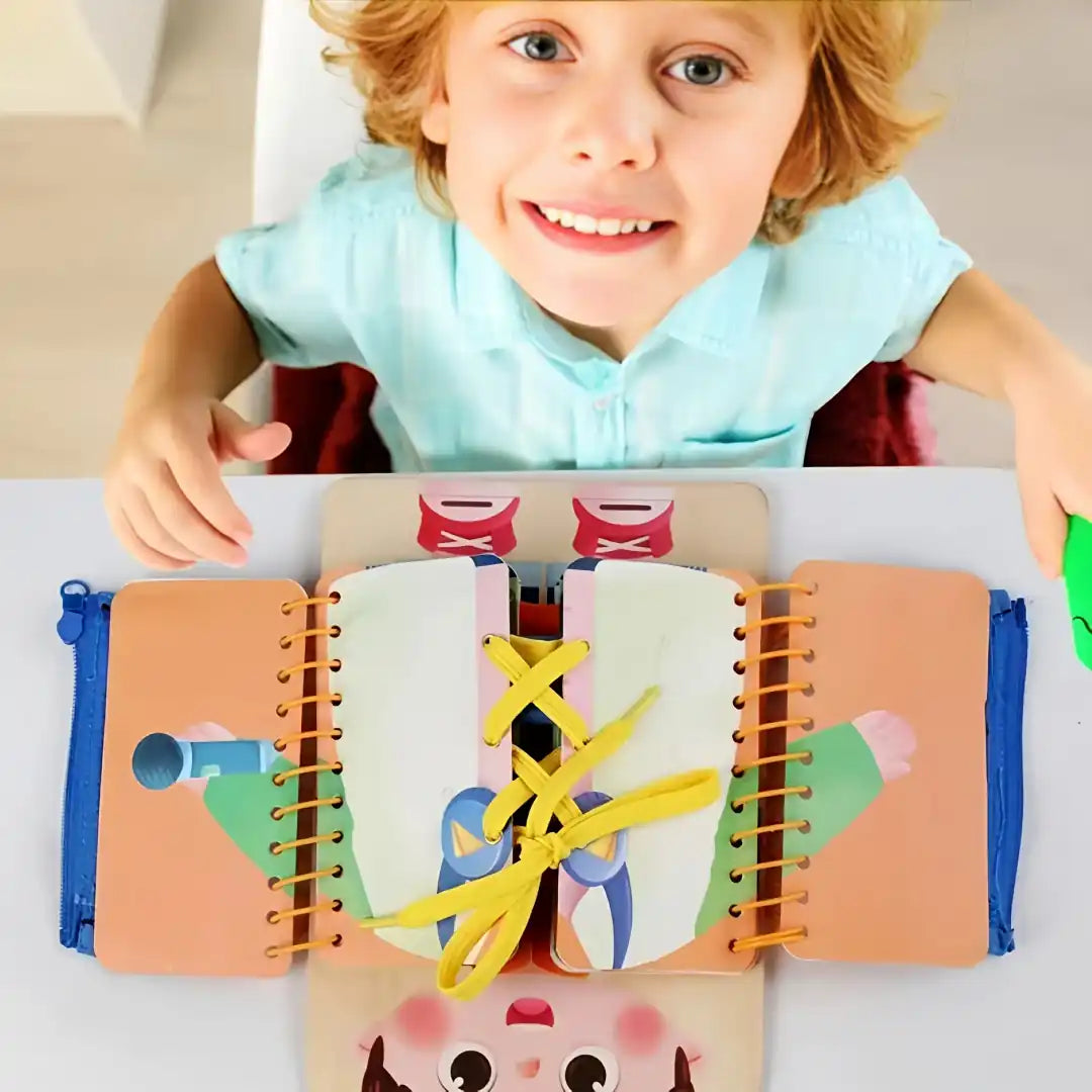 Smiling child playing with BusyTots quiet book, practising shoe tying and fine motor skills with colourful laces and zips.