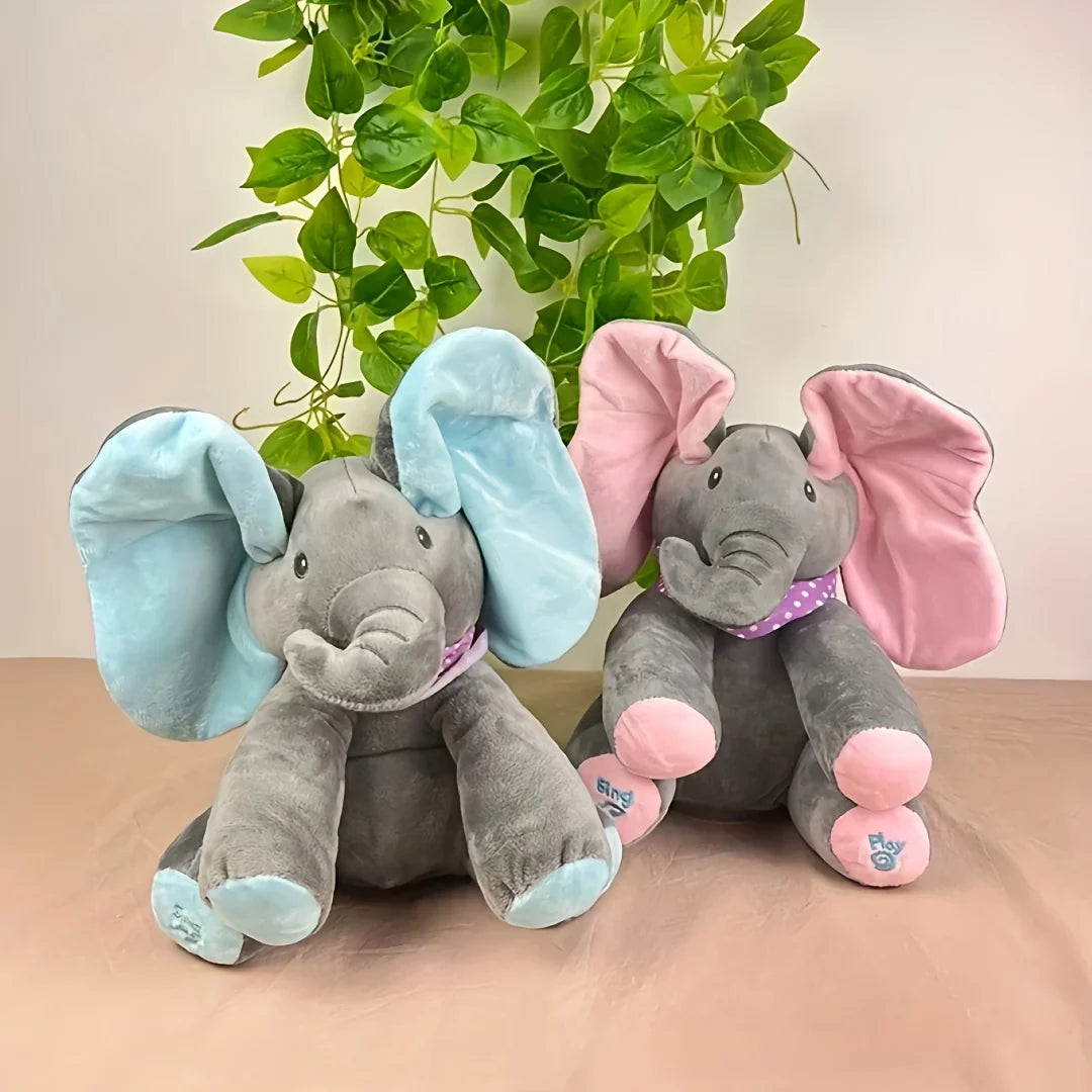Two cuddly elephant plush toys with soft grey fur and oversized ears – one with pink and one with blue accents – sitting side by side in front of leafy greenery, perfect for sensory play and snuggles.