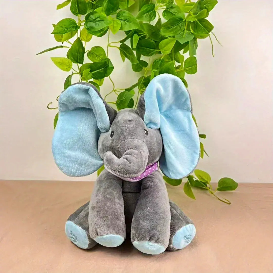 Interactive grey elephant plush toy with soft blue ears and feet, wearing a purple polka-dot scarf – perfect for cuddles, music and peek-a-boo fun.